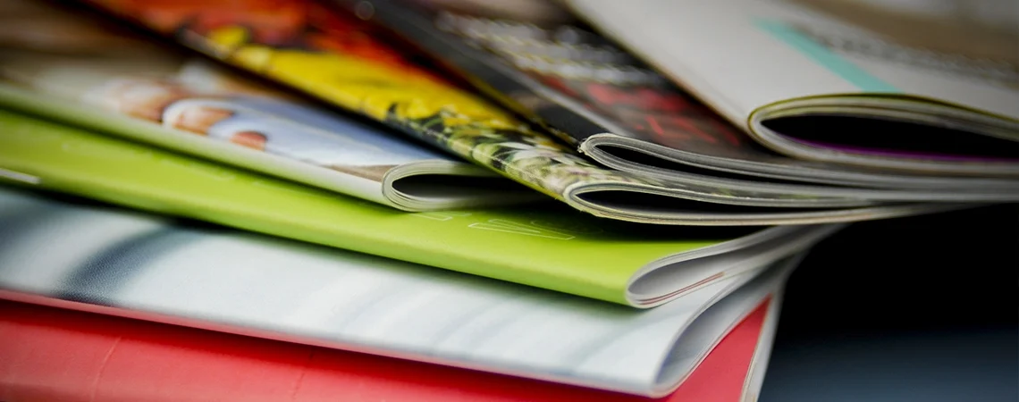 Pile de magazines colorés feuilletés sur une surface.